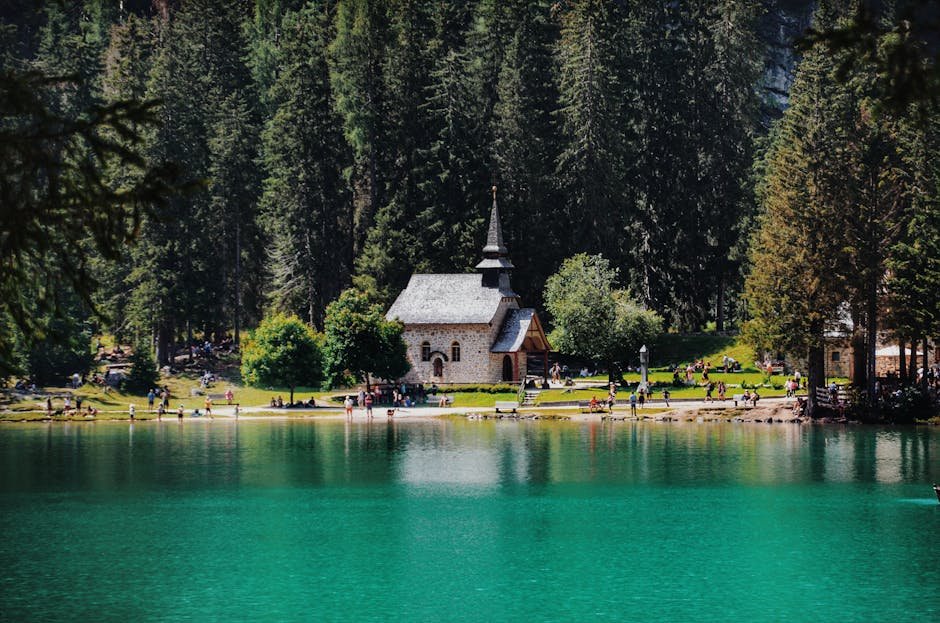A picturesque church by a serene lake surrounded by lush forest, offering a peaceful countryside view.
