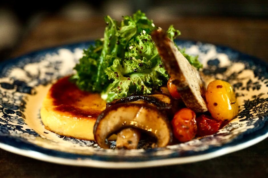 Delicious gourmet dish featuring mushrooms, sauteed greens, polenta, and cherry tomatoes served on a vintage plate.